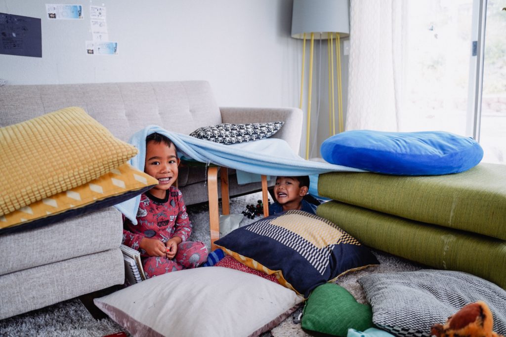 Brothers building a fort and enjoying indoor summer activities for kids