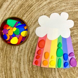 A fun spring craft for kids to sort coloured pebbles on a cutout rainbow.