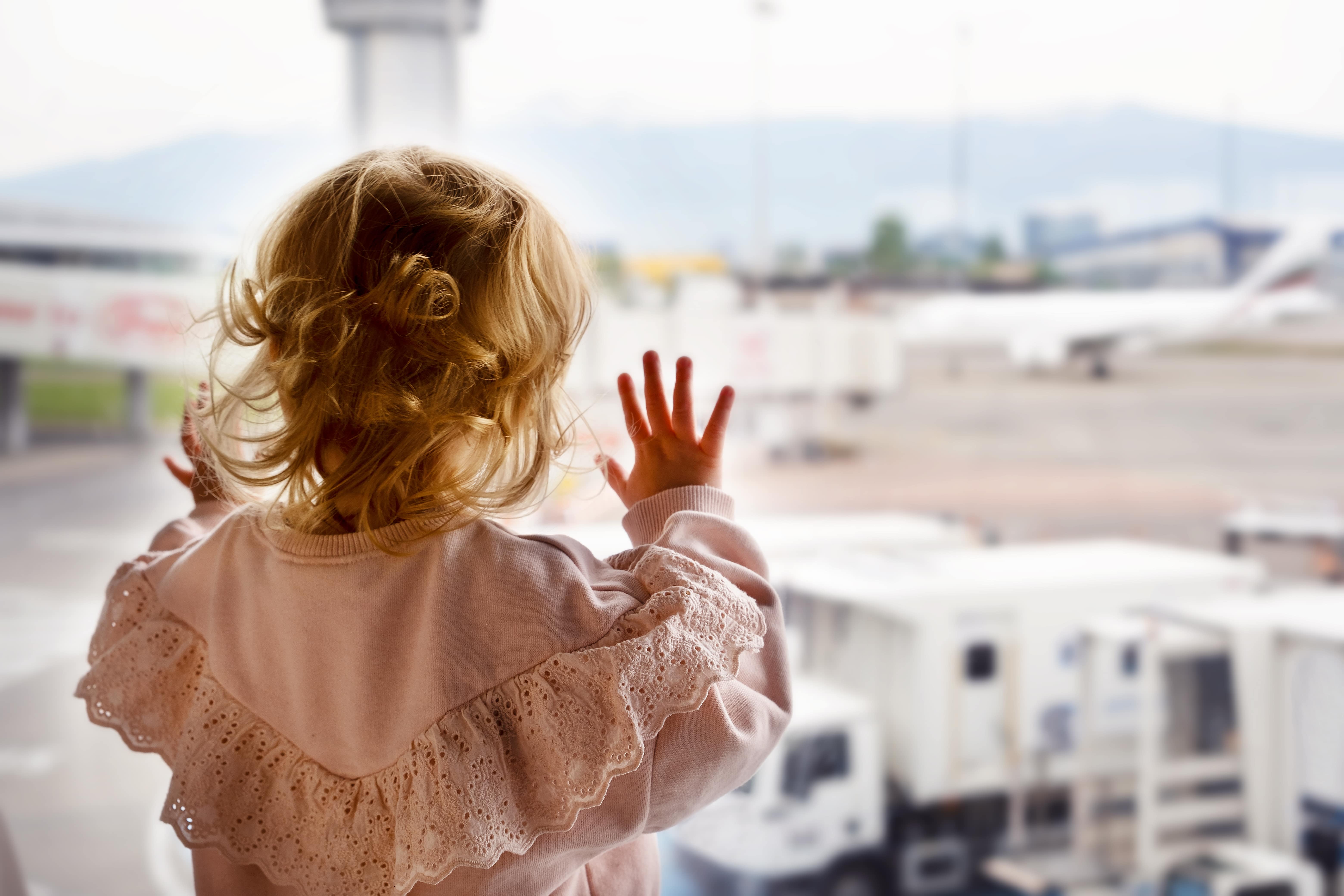 A toddler in an airport looking out at the planes. Read more for tips for travelling with a baby or toddler. 