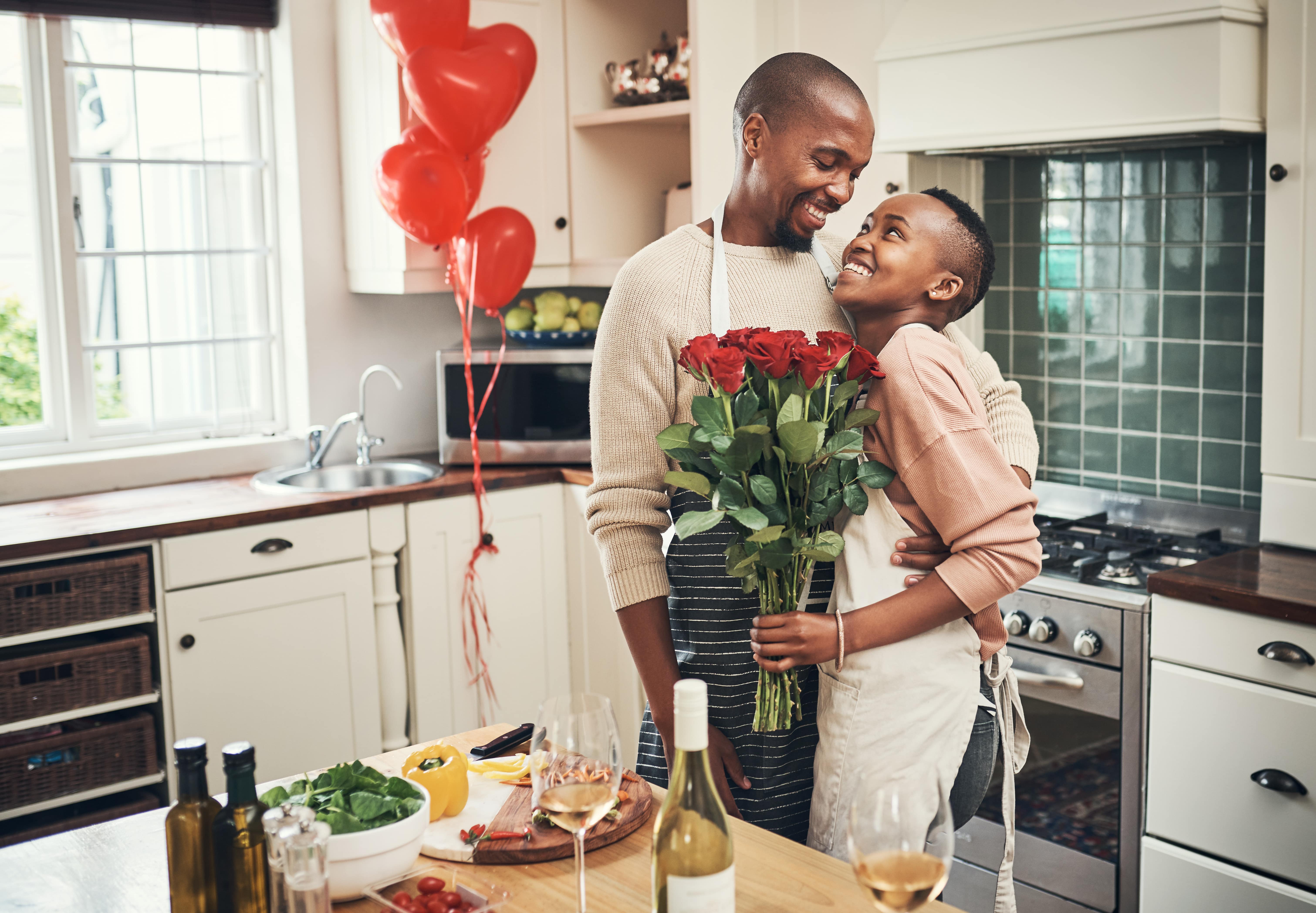 A young couple making dinner together enjoying self-care tips for parents on Valentine's Day. 