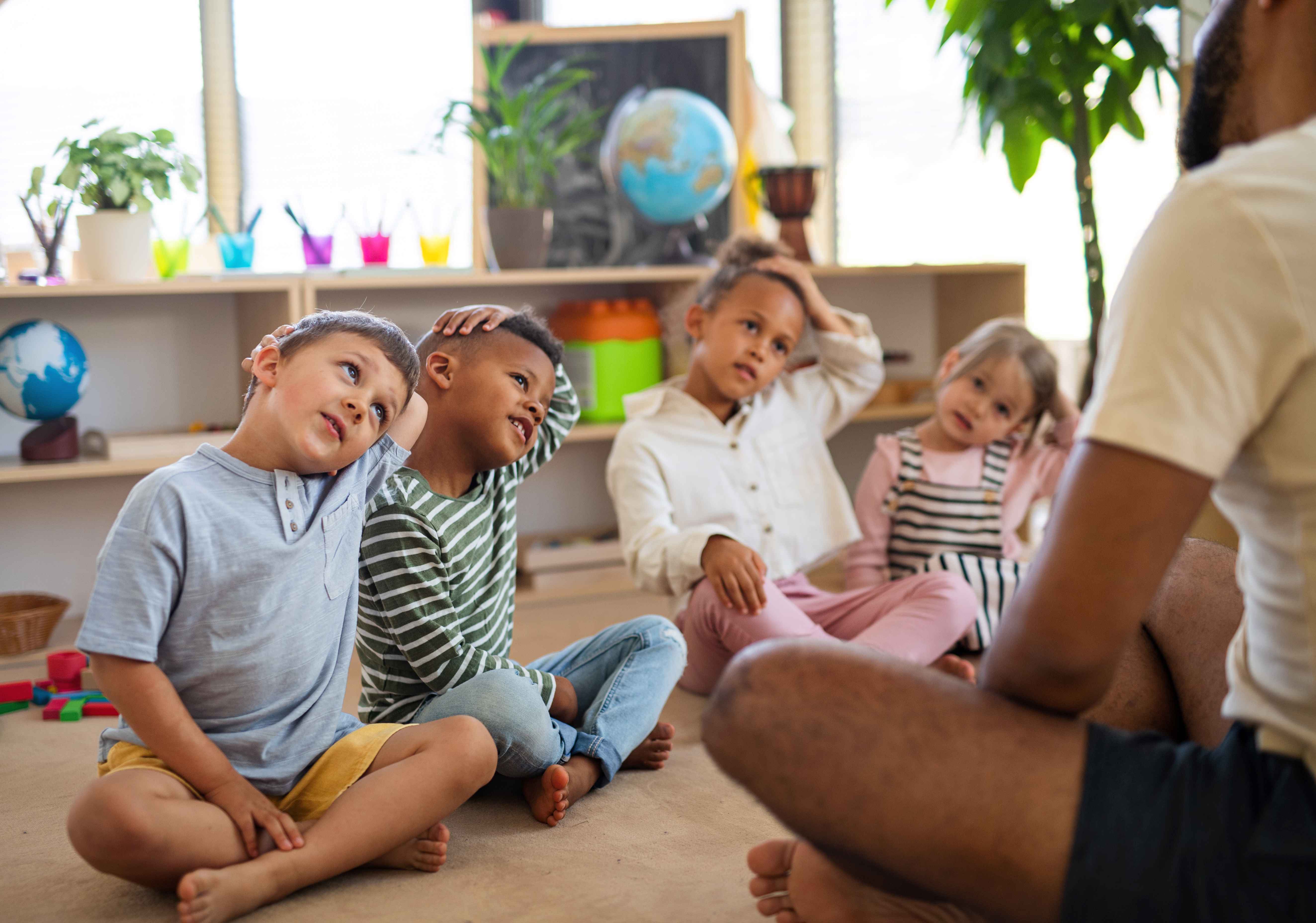 children sitting in a daycare with their teacher