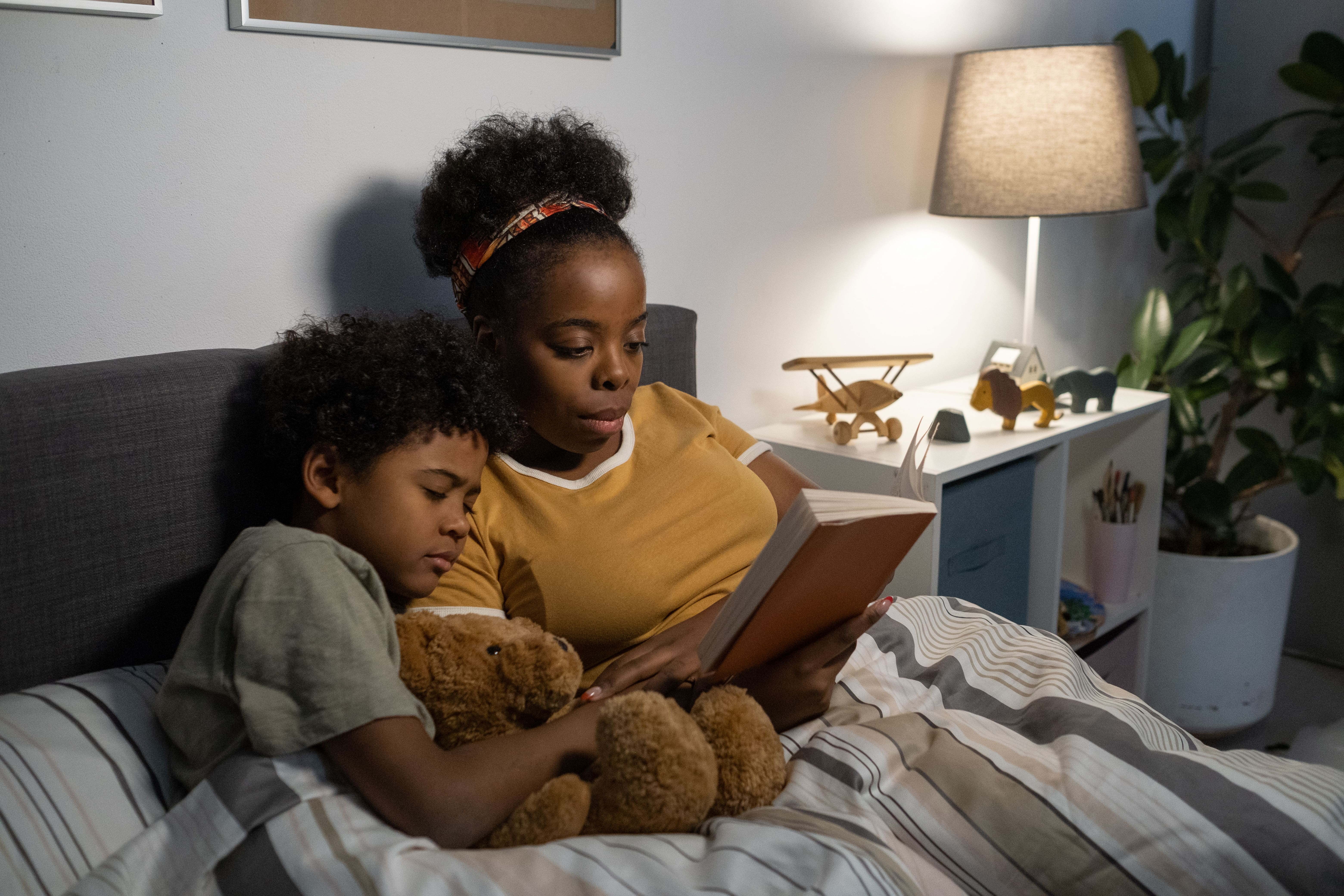 A mother in bed with her son reading him a bedtime story as part of their bedtime routine.